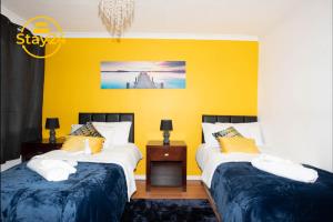 two beds in a room with a yellow wall at Penryn place in Milton Keynes
