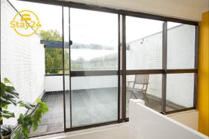 a balcony with glass doors and a chair at Penryn place in Milton Keynes