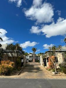 a driveway leading to a house with palm trees at Tyger Valley Villa in Durbanville