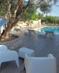 a pool with tables and benches next to a tree at Villa di Pasquale in Peschici