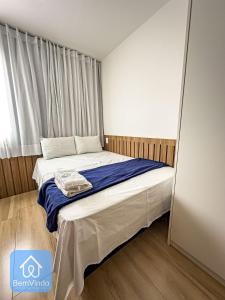 um pequeno quarto com uma cama com lençóis azuis em Estadia Confortável: Studio no Smart Pituba em Salvador