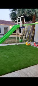 a green slide in a yard with green grass at شاليه تريك in Buraydah