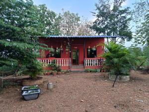 una casa roja con un porche delantero y árboles en Kittur Guest House, en Dharwad