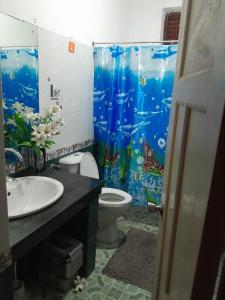 a bathroom with a toilet and a blue shower curtain at Leisure home in Colombo