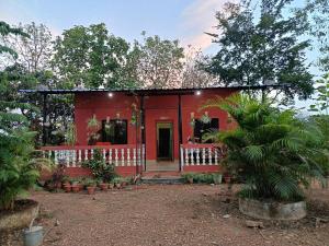 una casa rossa con veranda in giardino di Kittur Guest House a Dharwad