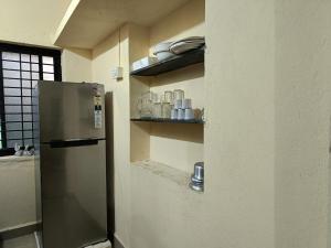 una cucina con frigorifero in acciaio inossidabile e scaffali di Kittur Guest House a Dharwad