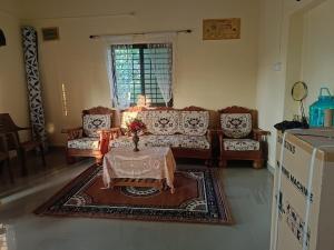 un soggiorno con divani e un tavolo in una camera di Kittur Guest House a Dharwad
