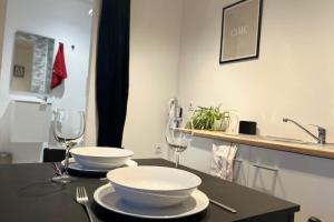 una mesa con dos tazones blancos y copas de vino en Cosy Rent Strasbourg TV Wifi Studio Gare 4, en Estrasburgo