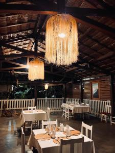 une salle à manger avec des tables blanches et des lustres dans l'établissement Chris Espace, à Toliara