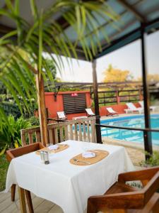 une table blanche avec des chaises et une piscine dans l'établissement Chris Espace, à Toliara