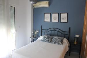 1 dormitorio con 1 cama con pared azul en Apartamento en Ciudad Jardin en Málaga