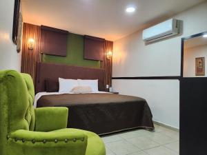a bedroom with a bed and a green chair at Royal Madero Inn Express in Tampico