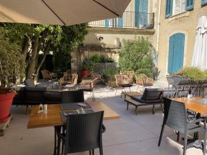 d'une terrasse avec des tables, des chaises et un parasol. dans l'établissement Château de Servanes, à Mouriès