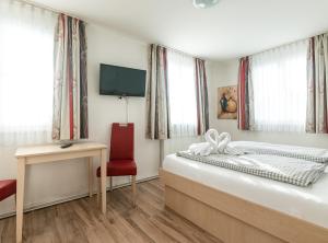 Schlafzimmer mit einem Bett, einem Schreibtisch und einem TV in der Unterkunft Gasthaus Traube, Ludwigshafen, Bodensee, Seenah gelegen in Bodman-Ludwigshafen