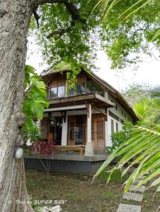 una casa con un porche y un árbol en Villa Watumita Sikka, en Hitokalak