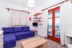 a living room with a blue couch and a balcony at Panagiotis Beach House Fourka 1 bedroom/5 guests in Skála Foúrkas