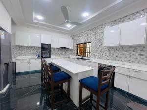 a kitchen with white cabinets and blue chairs at Luxe Club in Cotonou