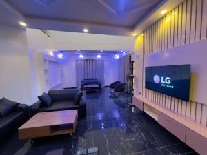 a living room with a couch and a large tv at Luxe Club in Cotonou
