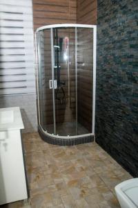 La salle de bains est pourvue d'une douche avec une porte en verre. dans l'établissement La pépite, à Cotonou