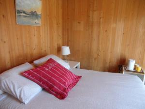 een slaapkamer met een wit bed en een rood kussen bij Les Fougères in Sévrier