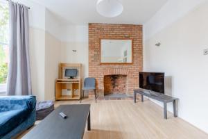 een woonkamer met een bank en een open haard bij Roomy 3BD by Hampstead Heath! in Londen