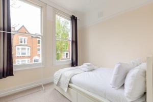 een witte slaapkamer met een bed en een raam bij Roomy 3BD by Hampstead Heath! in Londen