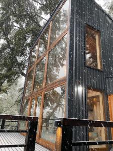 a black cabin with large windows in the snow at Lodge Rincon del Bosque, Malalcahuello in Malalcahuello
