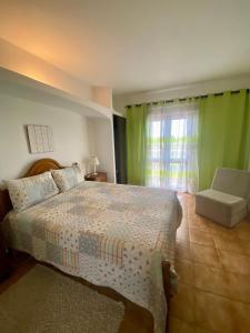ein Schlafzimmer mit einem Bett, einem Stuhl und einem Fenster in der Unterkunft Vivenda Silvestre in Albufeira