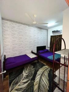 a living room with purple beds and a fan at ANGGUN HOMESTAY Banting in Banting