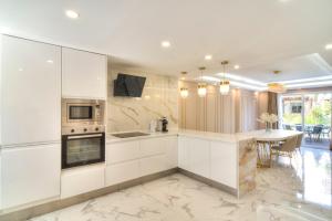 eine Küche mit weißen Schränken und einem Tisch mit Stühlen in der Unterkunft Serenity Luxury , Puerto Banús Marbella in Marbella