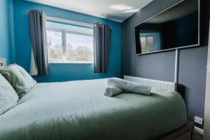 a blue bedroom with a bed and a window at Hullidays 3 bed House Hull West Calvert in Hull