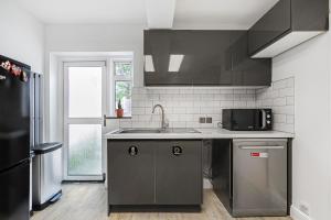 a kitchen with a sink and a black refrigerator at Casa Dolce in London