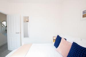 a white bedroom with a white bed with blue pillows at Northern Hideaways Castle Hill View, Bellingham in Bellingham