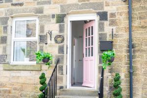 a pink door on a stone house with potted plants at Northern Hideaways Castle Hill View, Bellingham in Bellingham
