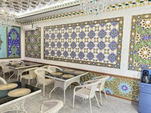 a restaurant with tables and chairs and colorful tiles on the wall at Hotel Khalid in Bukhara