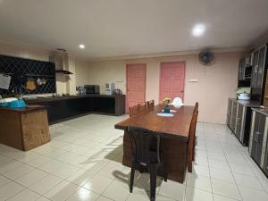 uma grande cozinha com uma mesa de madeira e cadeiras em Citadil Homestay em Miri