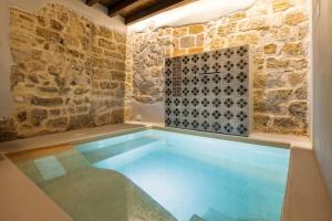 a swimming pool in a room with a stone wall at Sette Fate Suites & Spa in Palermo