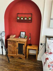 a room with a red wall with a table and a shelf at Premium Dighbeth in Birmingham