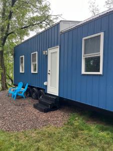 a blue tiny house with two chairs and a door at The Overlook Tiny Home in Elizabethtown