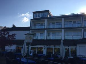 a hotel with chairs and umbrellas in front of it at Hotel Görres in Wachtberg