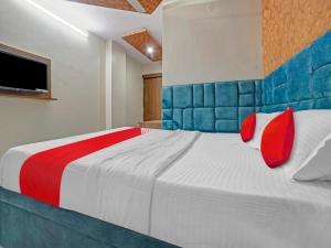 a bedroom with a large bed with red and blue pillows at All Seasons Corporate in Jamshedpur