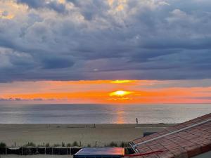 einen Sonnenuntergang am Strand mit Sonnenuntergang in der Unterkunft Atlantic Selection - Vue Océan avec terrasse, plage Notre-Dame in Capbreton