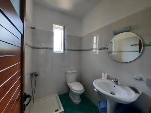 y baño con aseo, lavabo y espejo. en Amarildo Hotel, en Himare