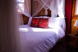 1 cama con sábanas blancas y almohadas rojas en Quiet Mind Lodge, Spa & Retreat Sequoias en Kernville