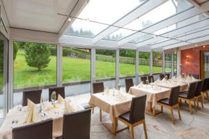 comedor con mesas y sillas y ventanas grandes en Hotel Pension Appartement Kristall, en Tröpolach