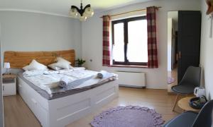 a bedroom with a large white bed and a window at Smrek Sokolec Agroturystyka in Ludwikowice Kłodzkie