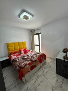 1 dormitorio con 1 cama con cabecero amarillo y ventana en شالية للايجار فى بورتو, en `Ezbet Shalabi el-Rûdi