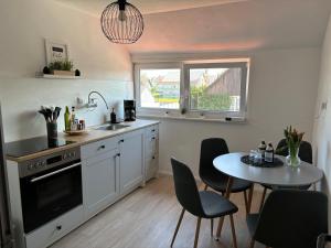 eine Küche mit einem Tisch, Stühlen und einem Waschbecken in der Unterkunft Ferienwohnung Alpenblick in Benningen