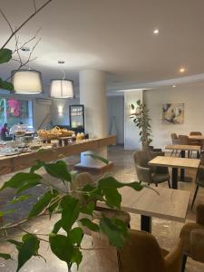 ein Wohnzimmer mit Tischen, Stühlen und einer Pflanze in der Unterkunft Grand Hôtel De Calvi in Calvi