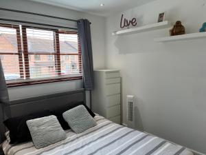 a bedroom with a bed with two pillows and a window at Chic & Modern Flat: Perfect for Exploring Kent! in Kent